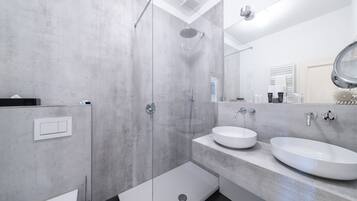 A modern bathroom with a glass-enclosed shower, two sinks, and a large mirror.