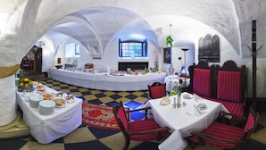 Un espace repas avec un sol à carreaux, des tables blanches et des chaises à revêtement rouge.