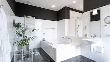 Un baño moderno con una paleta de colores blanco y negro, que incluye una bañera, un lavamanos y un espejo.