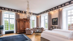 Une pièce spacieuse avec un grand lit, une armoire en bois, un canapé et un lustre.