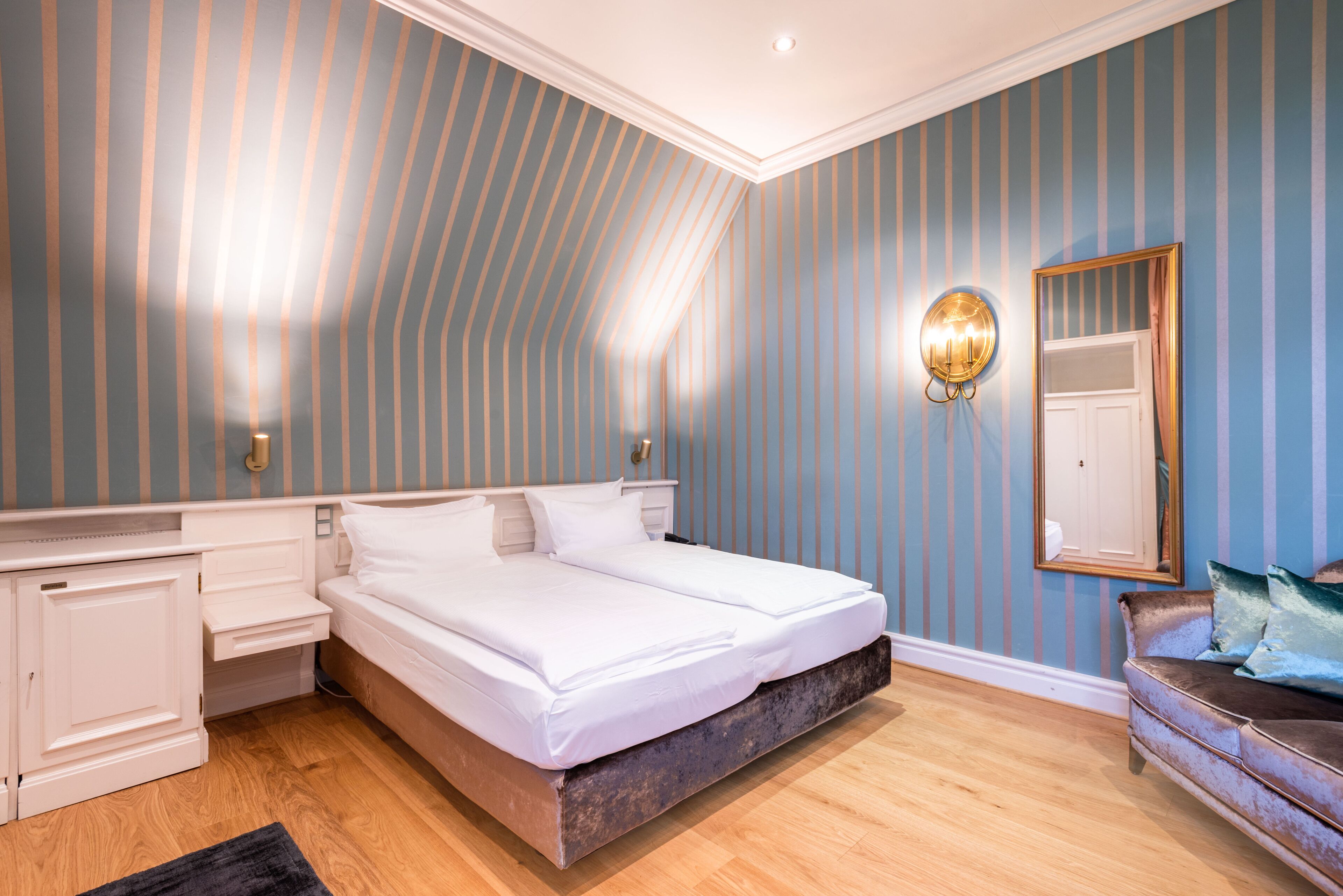 Ein Schlafzimmer mit einem großen Bett, einem Nachttisch, einer Kommode, einem Spiegel und Holzboden.
