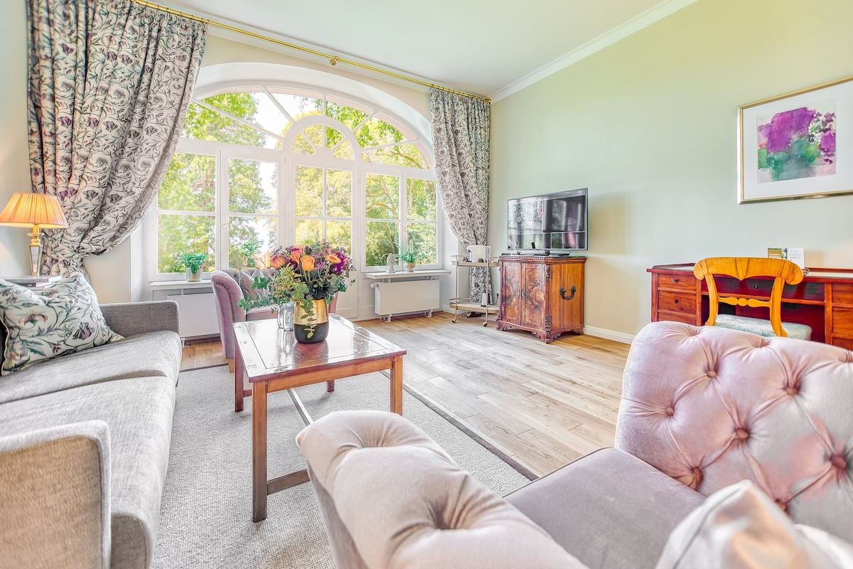 Ein Wohnzimmer mit einer Couch, einem Sessel, einem Couchtisch und einem Fernseher.