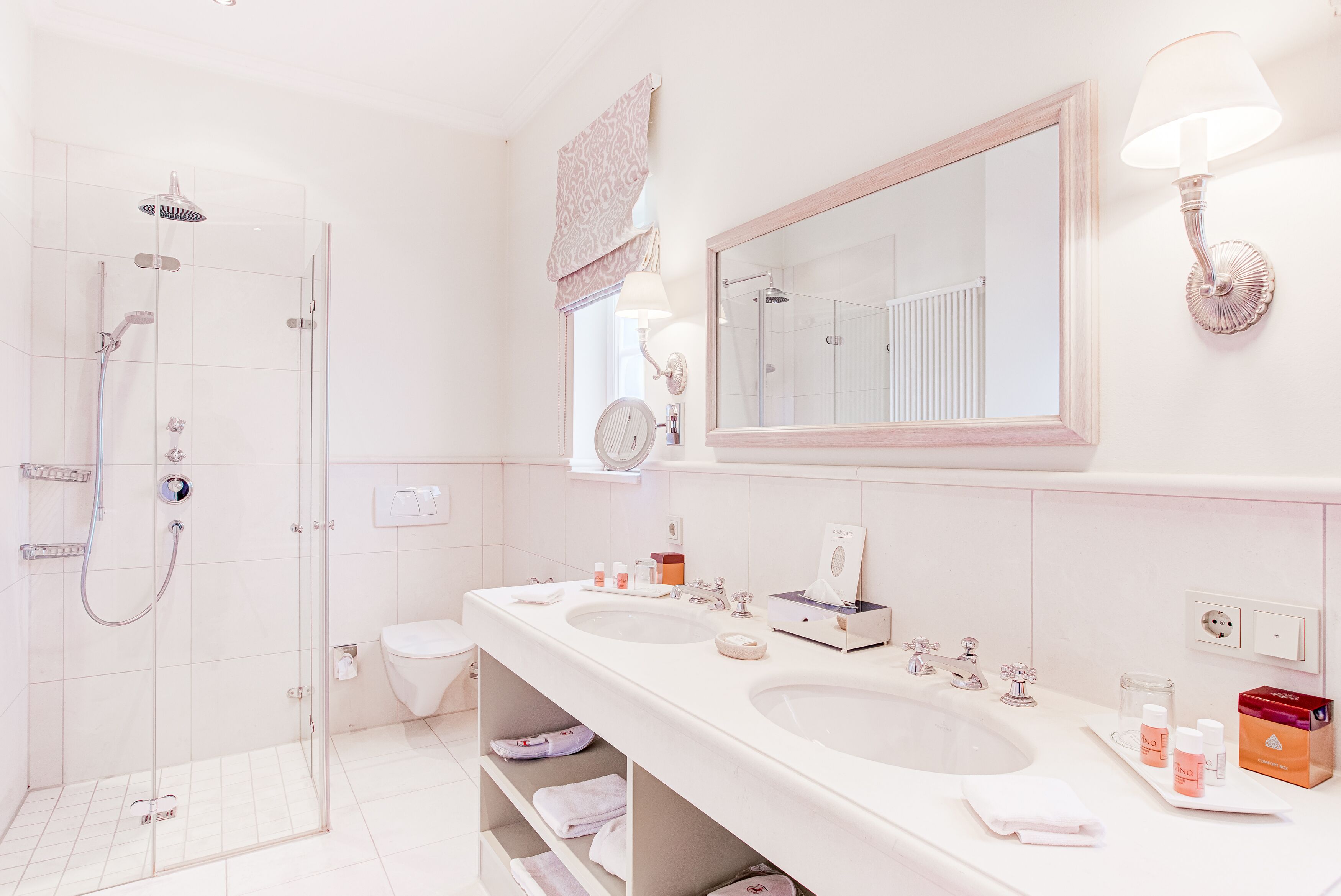 A modern bathroom with a glass-enclosed shower, a double sink vanity, and a large mirror.
