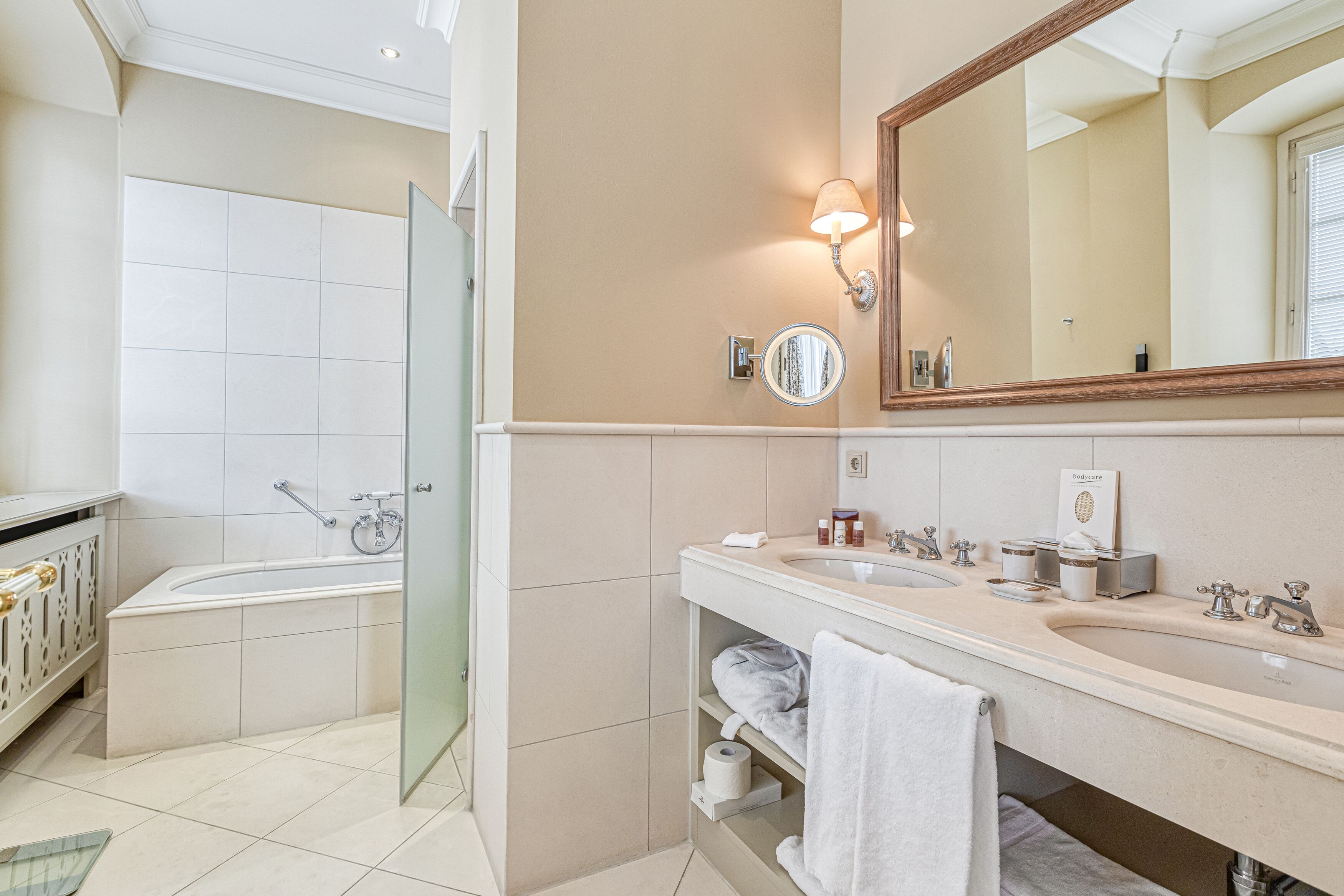 A modern bathroom with a bathtub, a large mirror, a vanity with a sink, and a toilet.