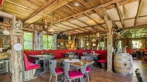 A rustic wooden interior with high ceilings, exposed beams, and a mix of seating arrangements including red cushioned benches and metal chairs. - Wald & Schlosshotel Friedrichsruhe (Zweiflingen-Friedrichsruhe)