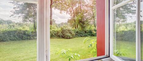 A window with a view of a well-maintained garden and trees.