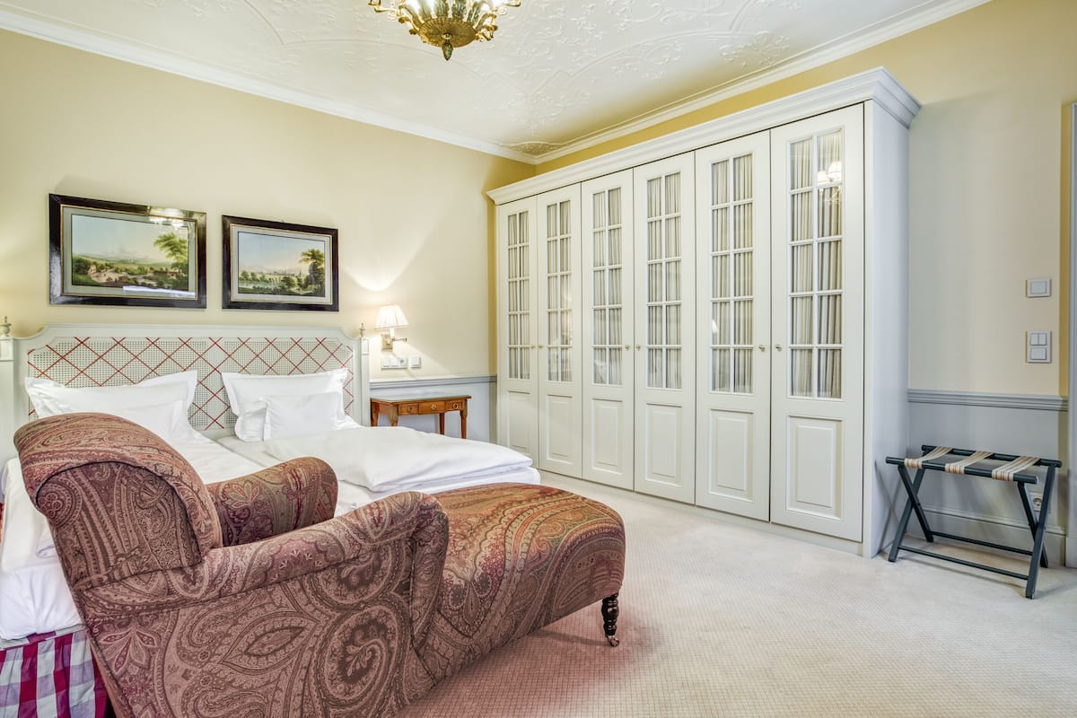 Ein Schlafzimmer mit Bett, Stuhl, Kleiderschrank und zwei gerahmten Bildern an der Wand.