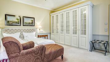 A bedroom with a bed, a chair, a wardrobe, and two framed pictures on the wall.