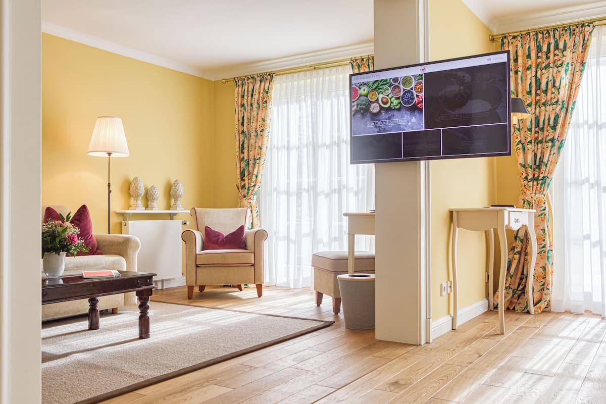 Ein Wohnzimmer mit einer Couch, einem Sessel, einem Couchtisch und einem an der Wand befestigten Flachbildfernseher.