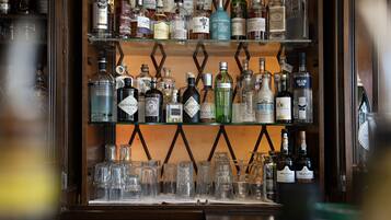 En bar med hylder fyldt med forskellige flasker spiritus og et udvalg af glas.