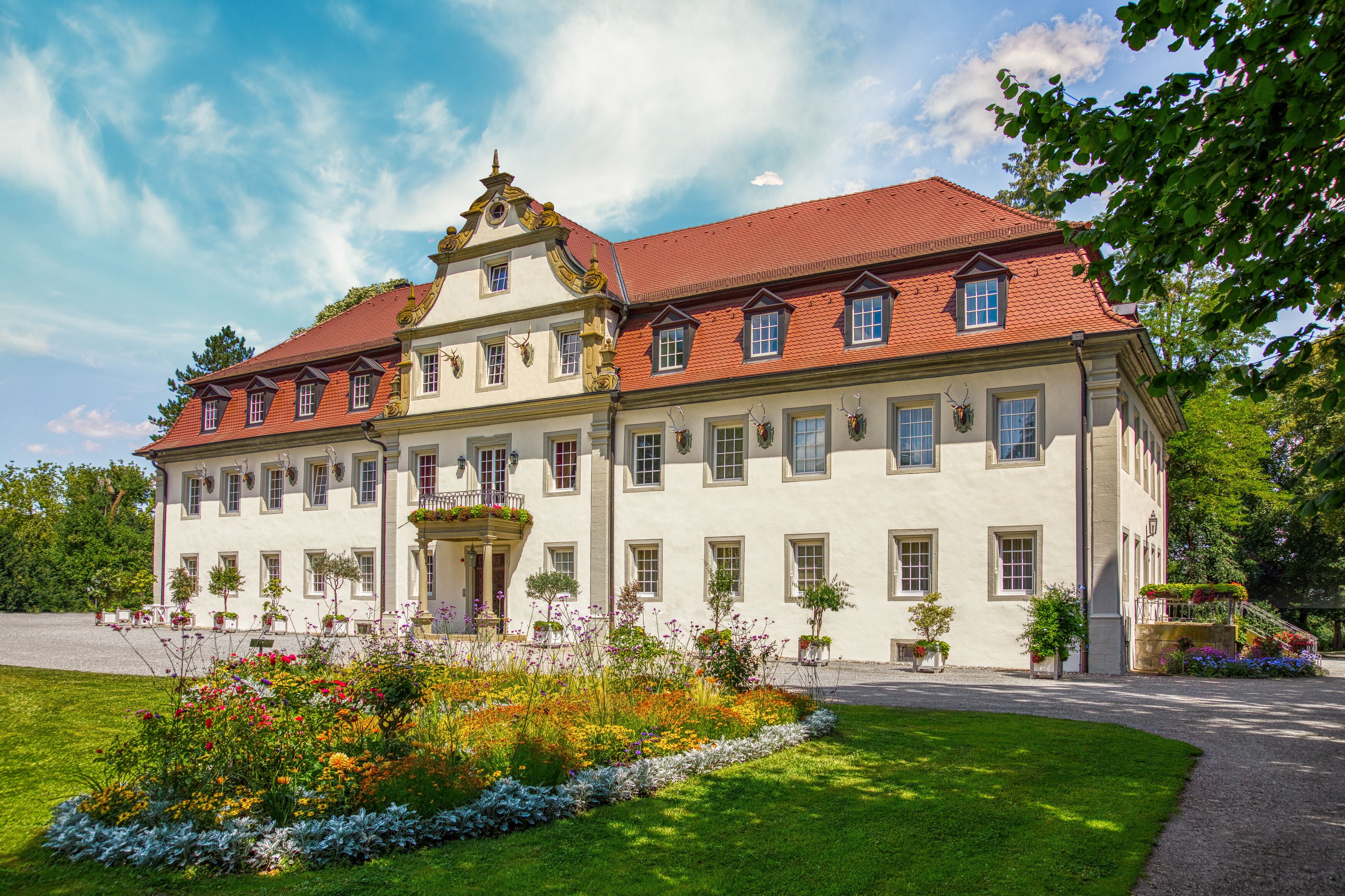 Ein großes, historisches Gebäude mit einer symmetrischen Fassade, zahlreichen Fenstern und einem roten Ziegeldach.