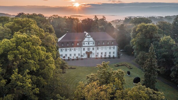 A large, white building with a symmetrical facade, surrounded by lush greenery and a well-maintained lawn. - Wald & Schlosshotel Friedrichsruhe (Zweiflingen-Friedrichsruhe)