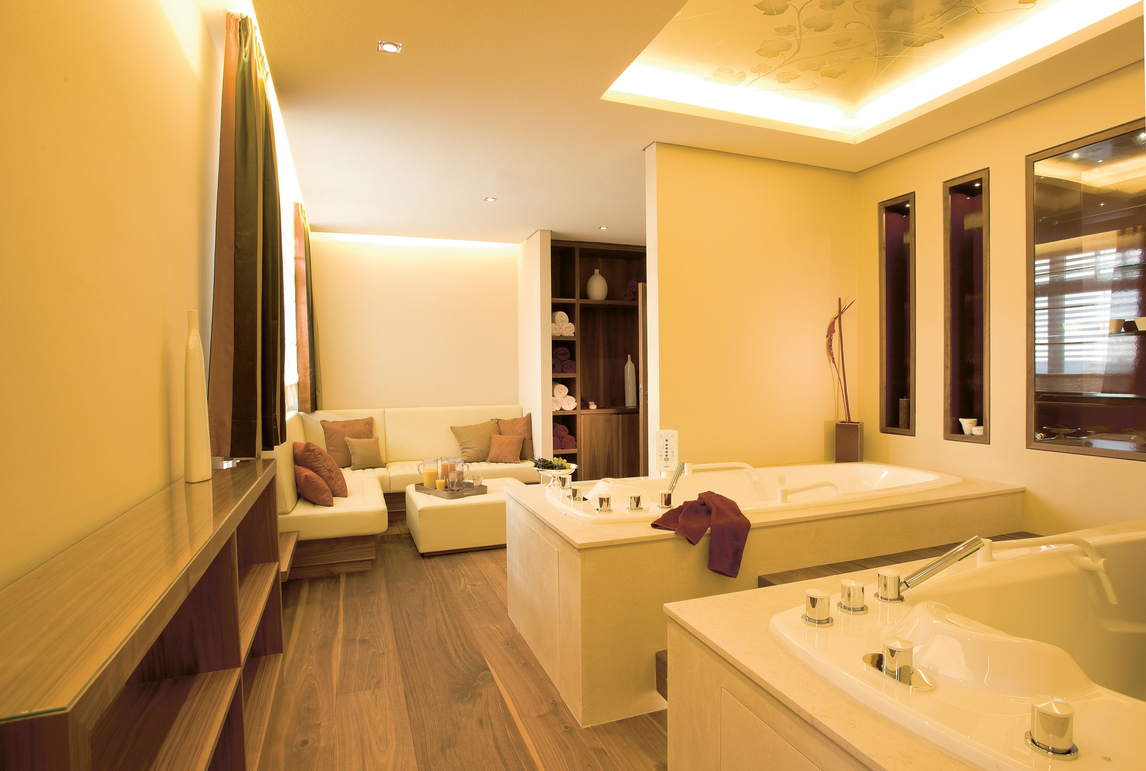 Ein modernes Badezimmer mit einer Badewanne, einem großen Spiegel und einer Sitzecke mit einer Couch.