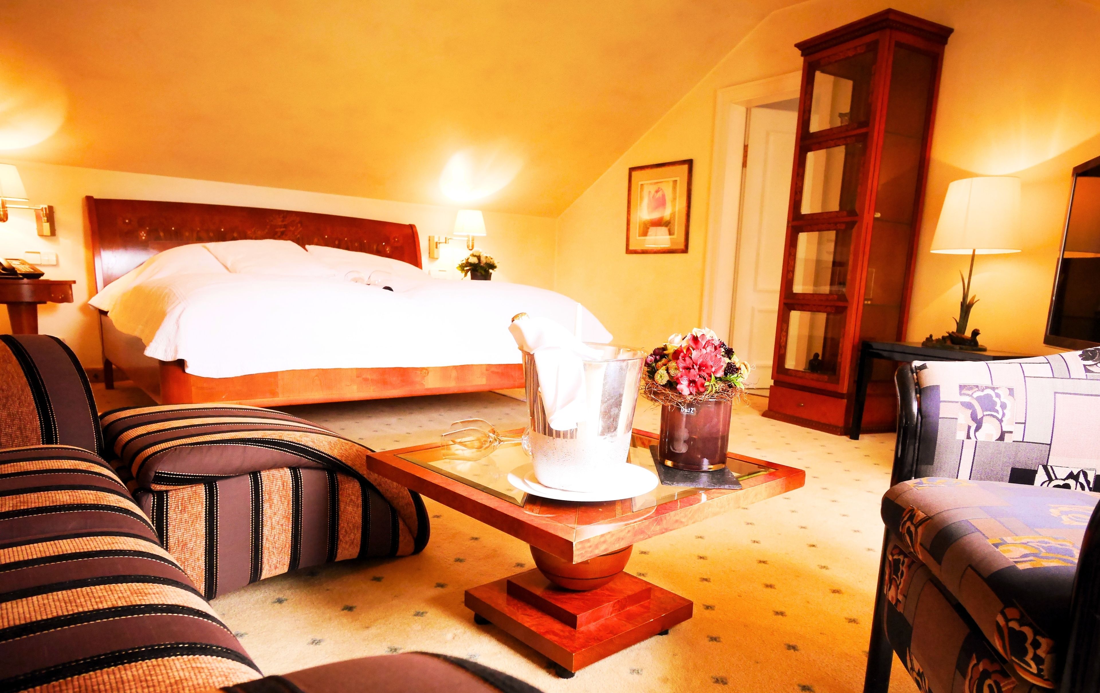 A hotel room with a bed, a sitting area with a table, and a cabinet.