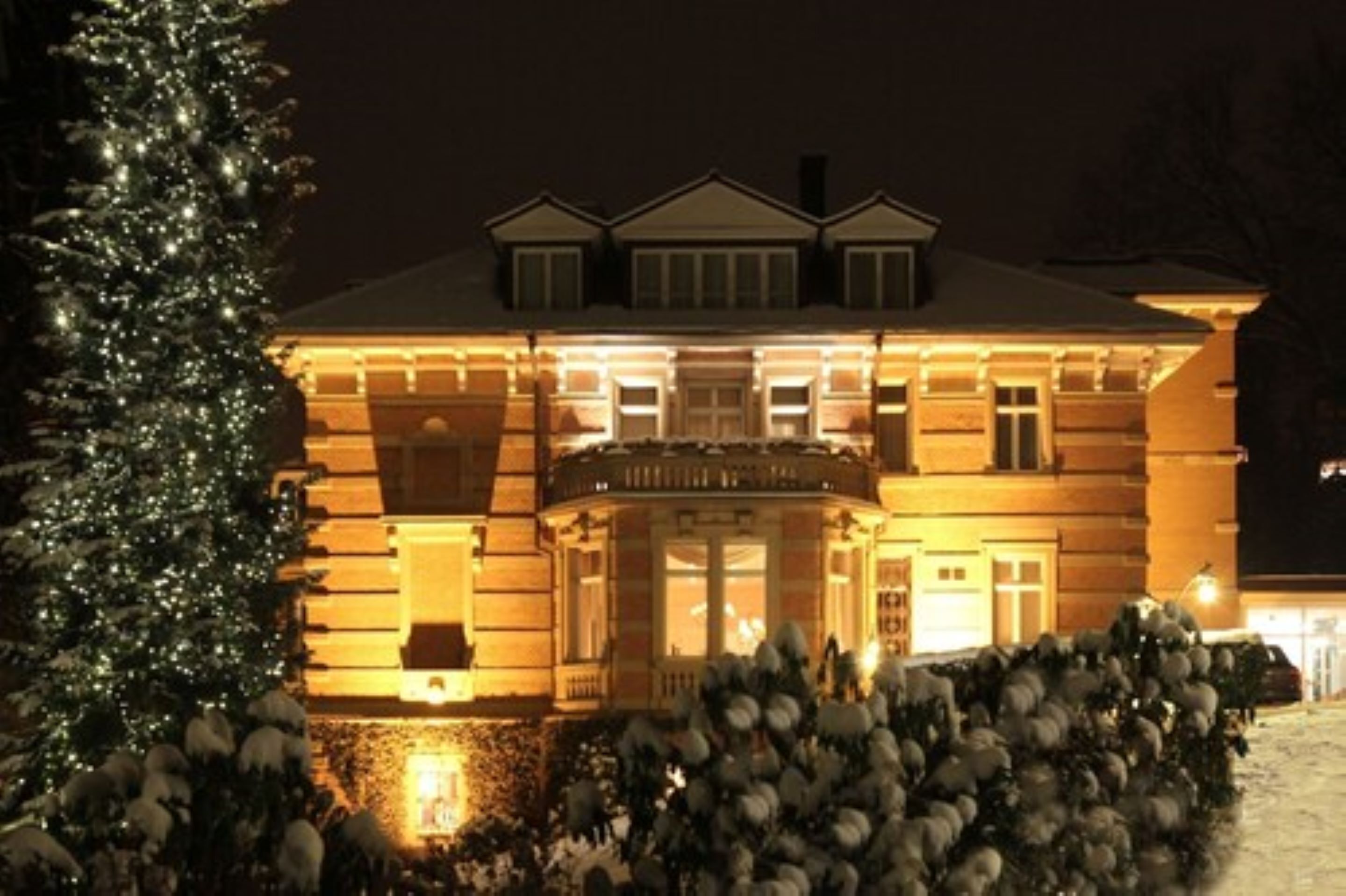 A large, two-story building with a symmetrical facade, a central entrance with a portico, and a snow-covered lawn.