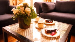 Una mesa de comedor con un arreglo floral, una tetera, tazas, platitos y una rebanada de pastel.