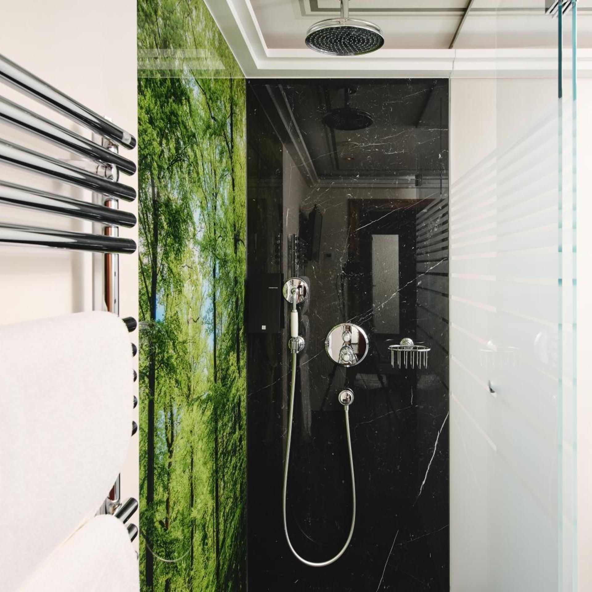 A modern bathroom with a glass shower enclosure, a white towel rack, and a marble wall.