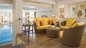 A modern hotel lobby with a pool, a sofa set, and a dining area. - Hotel Schwarzmatt (Badenweiler)