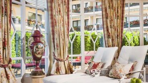 A room with a large window, white lounge chairs, and a decorative urn. - Hotel Schwarzmatt (Badenweiler)