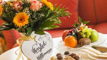 Une table ornée d’un arrangement floral, d’une assiette de fruits et d’une pancarte sur laquelle on peut lire : « Herzlich Willkommen ».