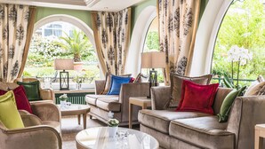 A spacious living room with a large sofa, armchairs, and a coffee table. There are two lamps and a potted plant on the side table. - Hotel Schwarzmatt (Badenweiler)