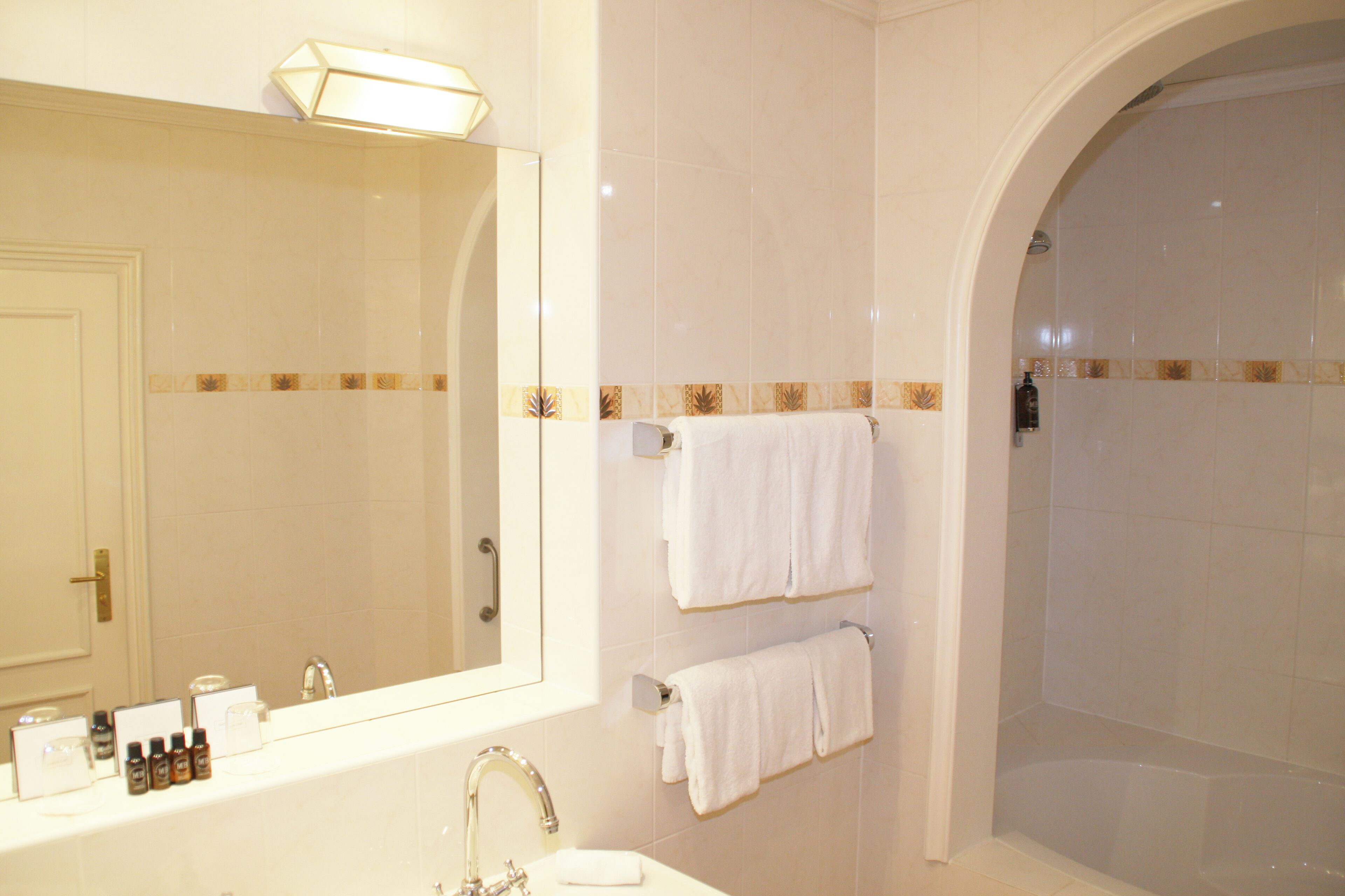 A bathroom with a large mirror, a sink, and a shower.
