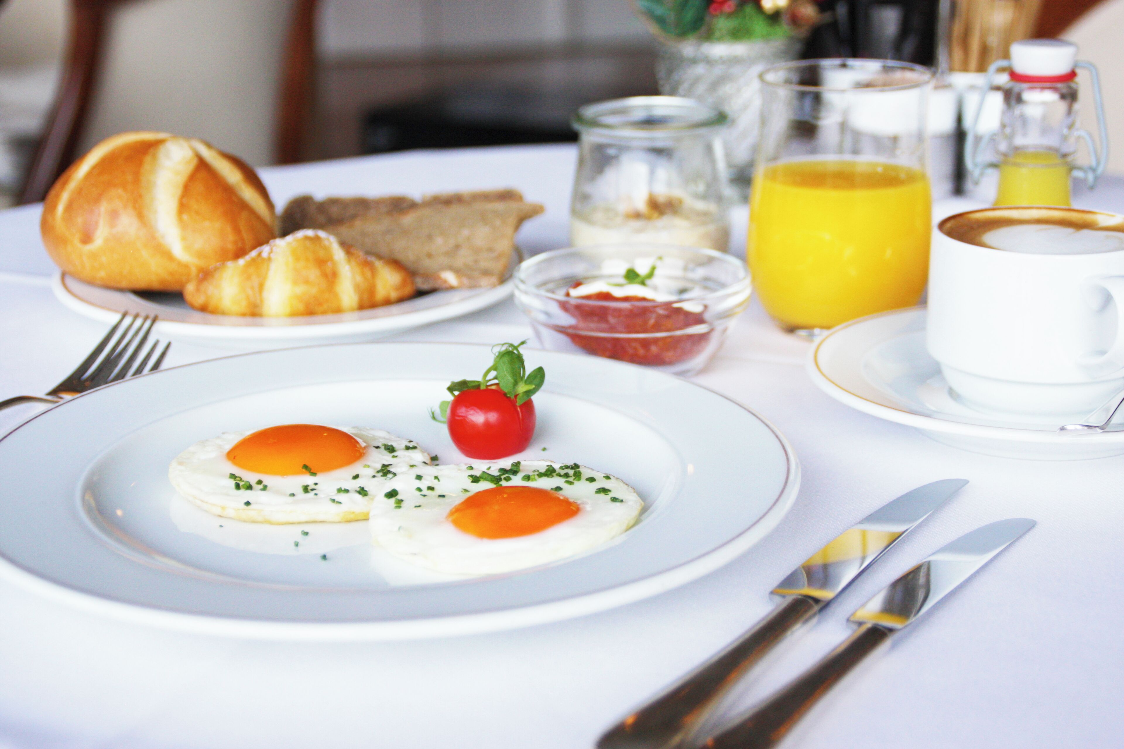 A breakfast setting with eggs, toast, and a glass of orange juice on a table.