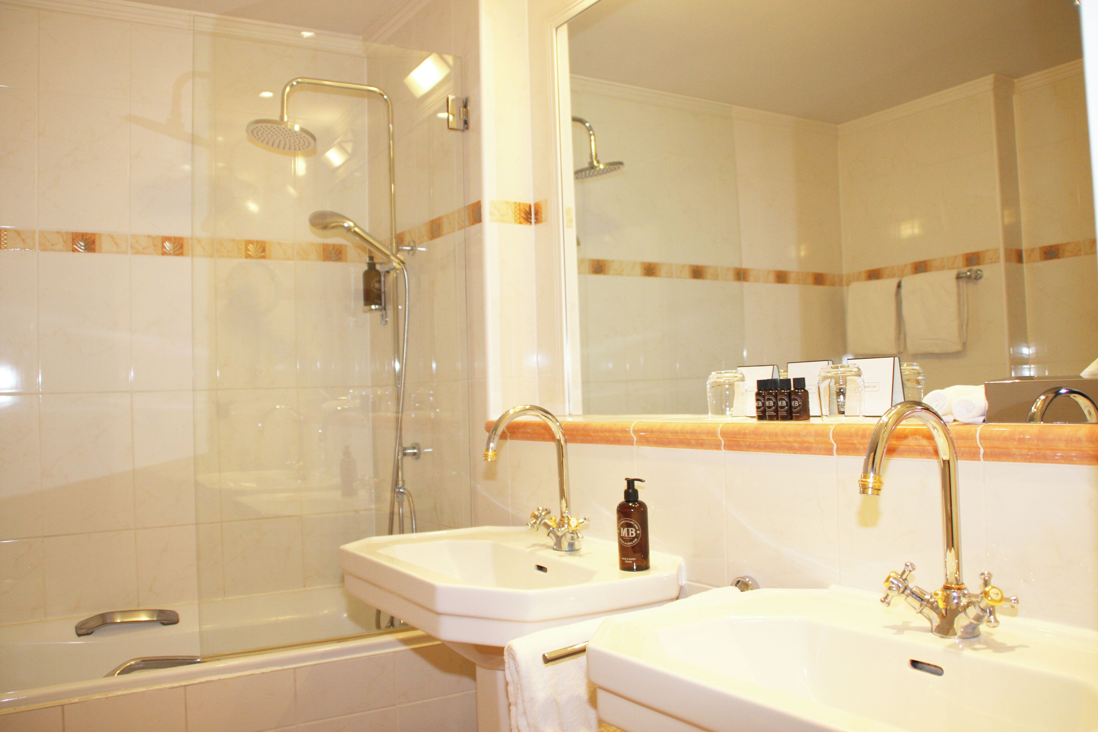A bathroom with two sinks, a bathtub, and a shower.