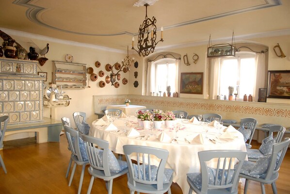 A dining room with a round table set for six, surrounded by six blue chairs with white polka dot cushions. - Boutique Hotel Residenz Winkler (Aschau im Chiemgau)