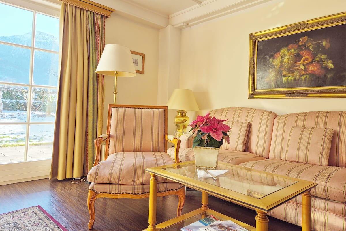 A room with a sofa, armchair, and a glass coffee table.