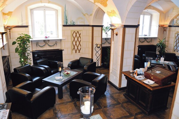 Un vestíbulo de hotel con asientos de cuero, una mesa de centro, chimenea y mostrador de recepción.