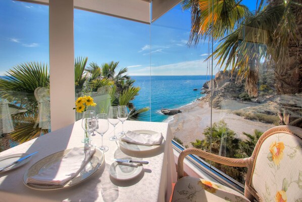 Une table dressée pour le dîner, avec vue sur l’océan et la plage.