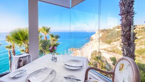 A table set for dining with a clear view of the ocean and a rocky landscape. - Hotel Servigroup Montíboli (Villajoyosa)