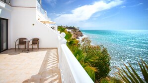 A balcony with two chairs and a table, overlooking a coastal view with clear blue water and a rocky shoreline. - Hotel Servigroup Montíboli (Villajoyosa)