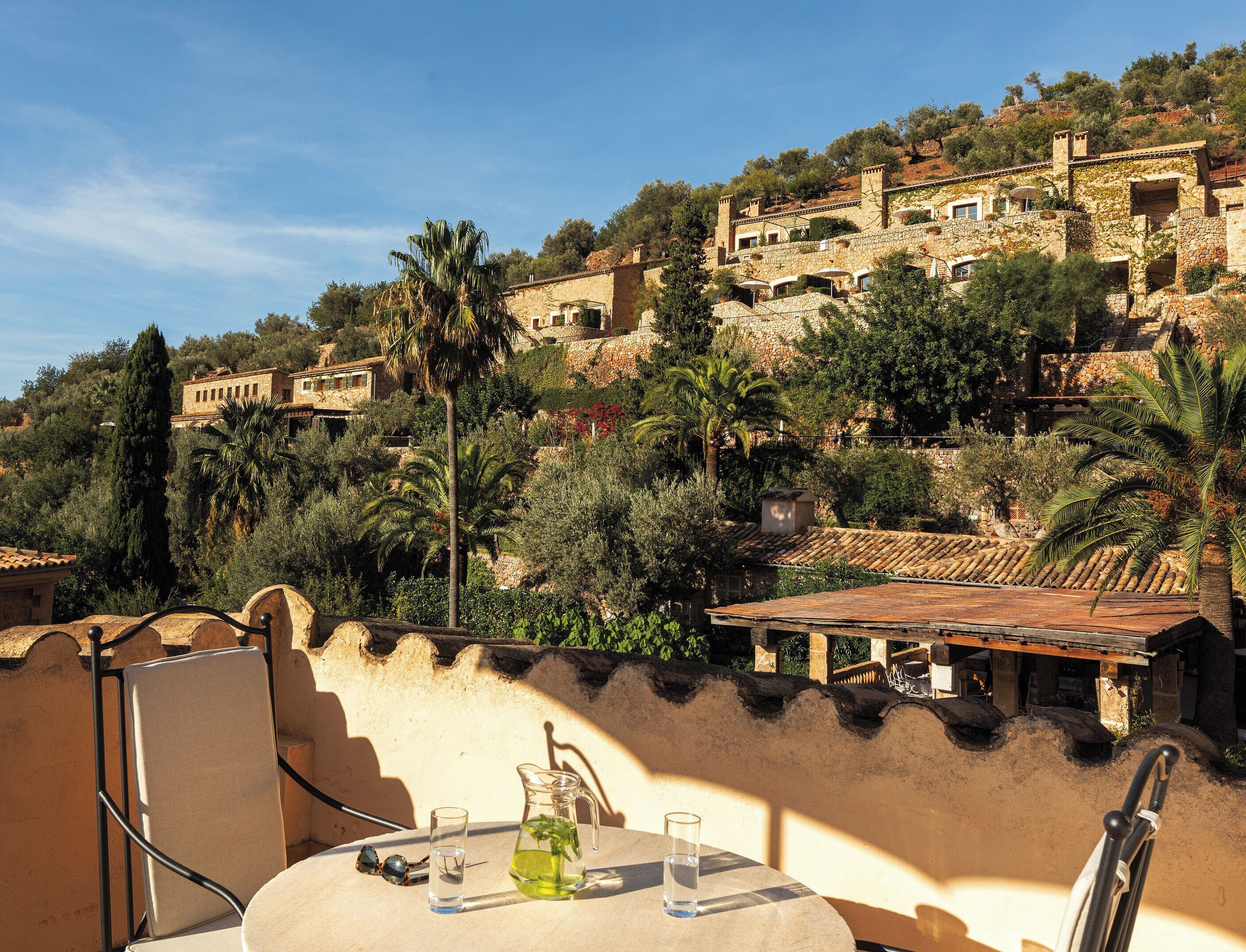 A terrace with a table, chairs, and a pitcher of water.