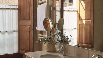 A bathroom with two sinks, a large mirror, and a window with wooden shutters.