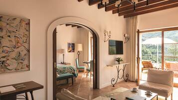 A room with a bed, a desk, a chair, a sofa, and a balcony with a view.