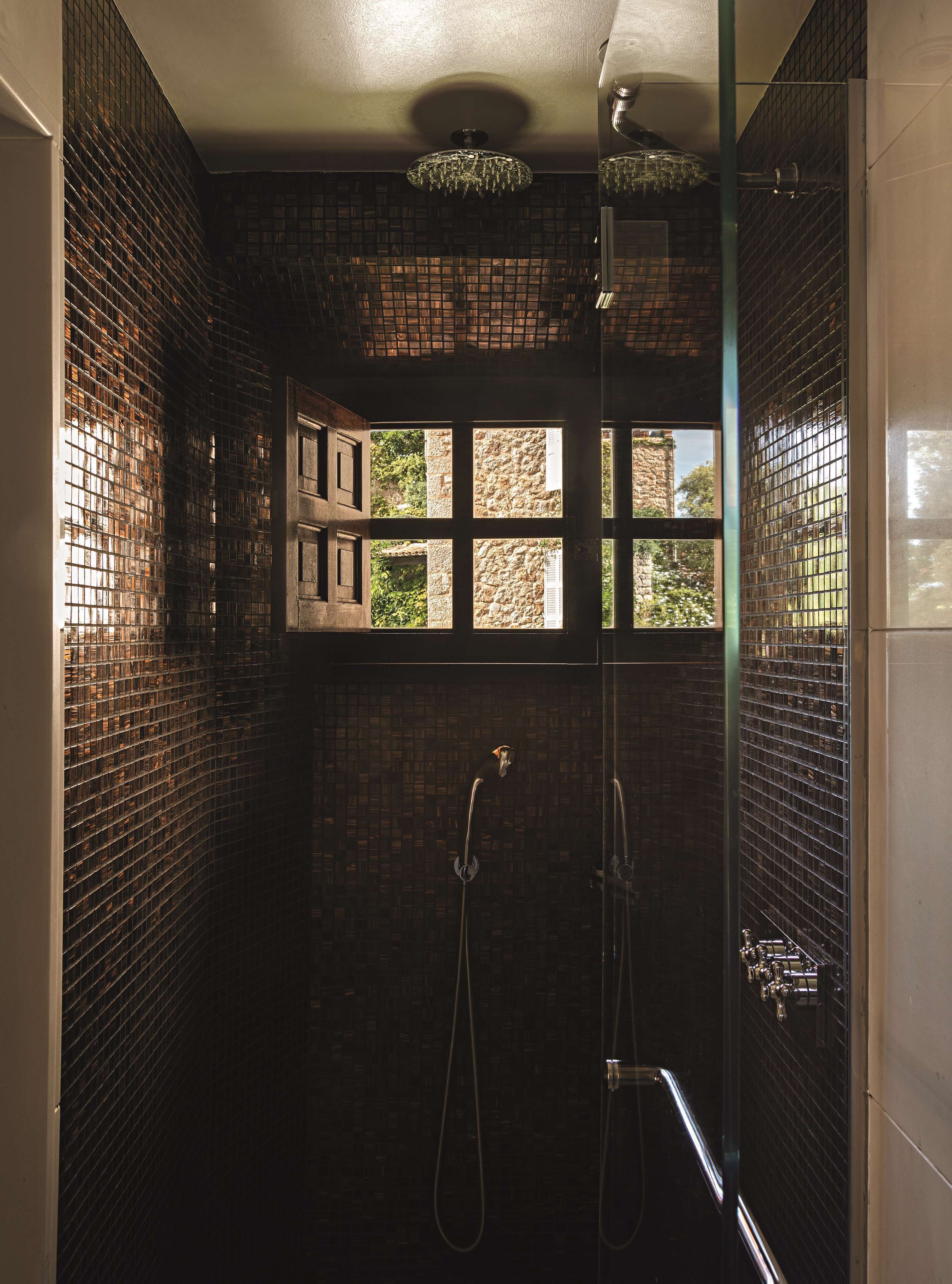 Une salle de bain avec un mur carrelé, une fenêtre donnant sur un espace verdoyant et un espace douche.