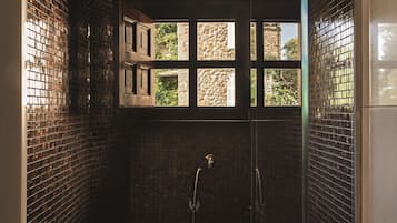 Une salle de bain avec un mur carrelé, une fenêtre donnant sur un espace verdoyant et un espace douche.