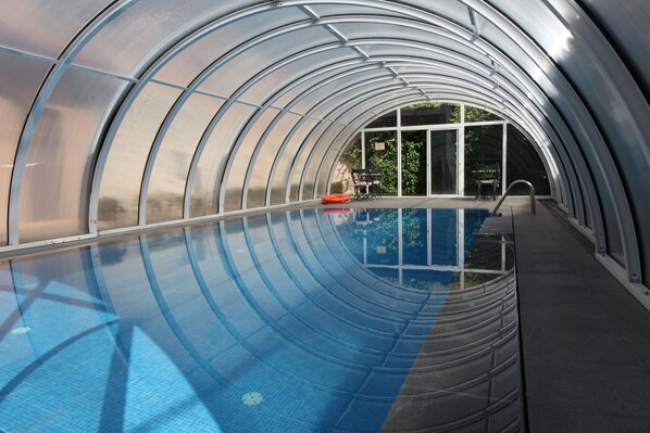 Una piscina cubierta, una piscina al aire libre, sombrillas, tumbonas