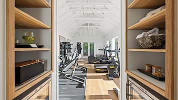 Un gimnasio con equipo de ejercicio, estanterías de madera y vistas al verdor.