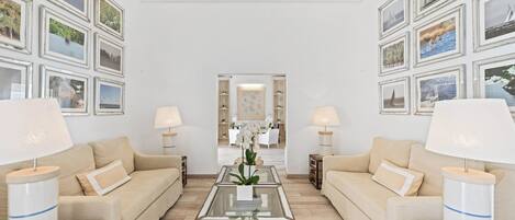 Una sala de estar moderna con dos sofás, una mesa de centro de cristal y cuadros en las paredes.