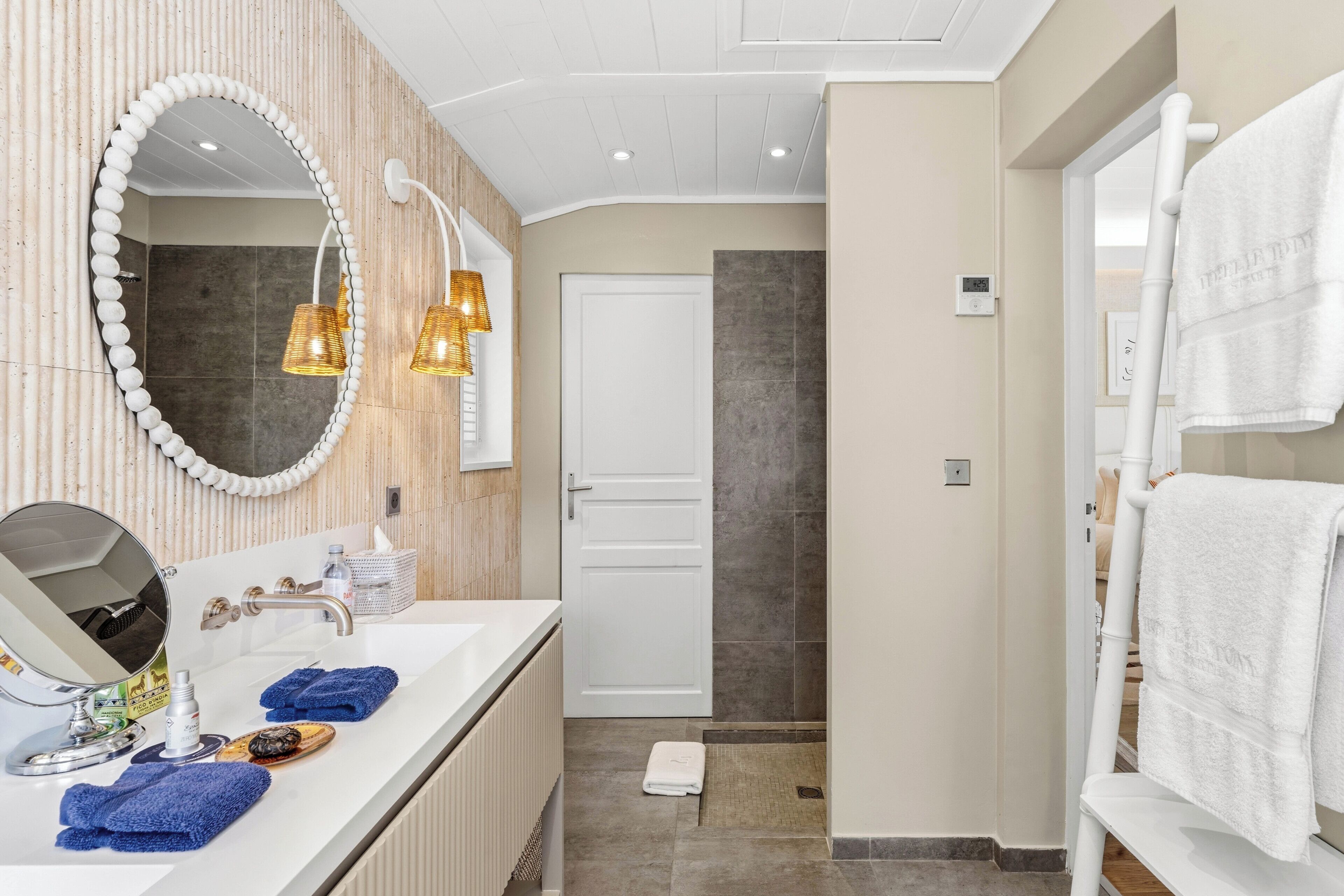 Un baño moderno con tocador, espejo, toallero y zona de ducha.