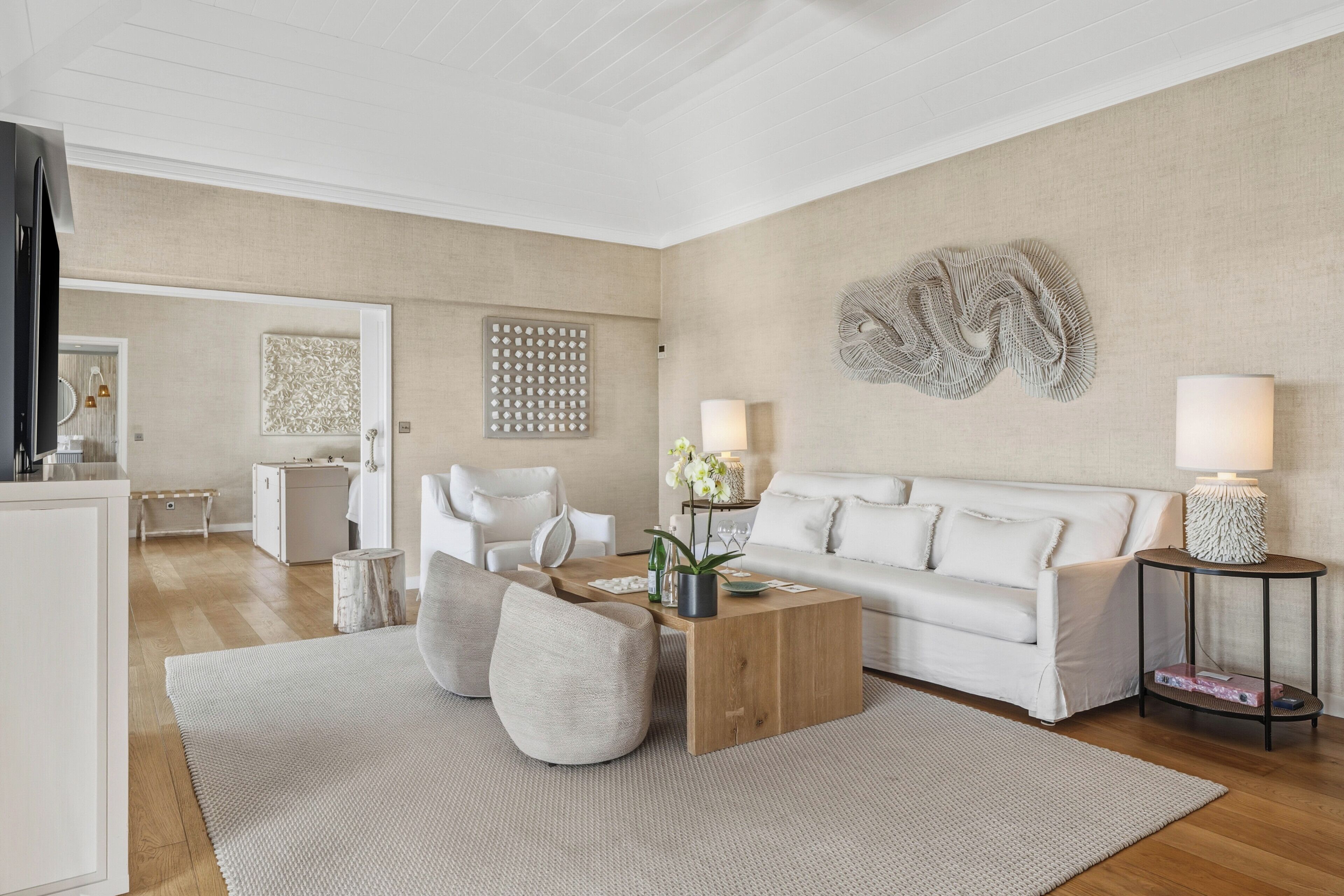 Ein modernes Wohnzimmer mit einem weißen Sofa, einem Holztisch und einem großen abstrakten Wandbild.