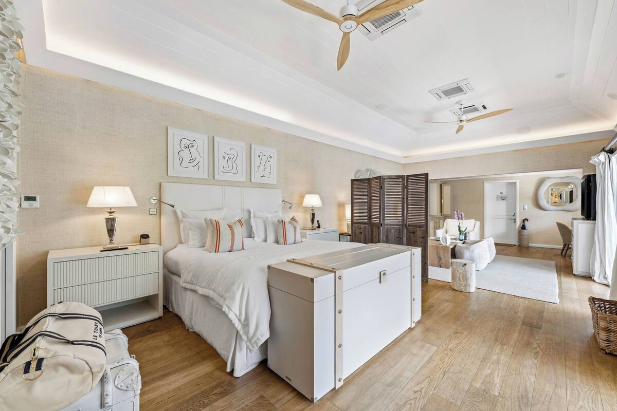 A spacious bedroom with a large bed, bedside tables, a wardrobe, and a ceiling fan.