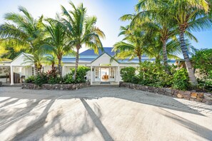 Un resort con entrada pavimentada, palmeras y un edificio con techo azul.