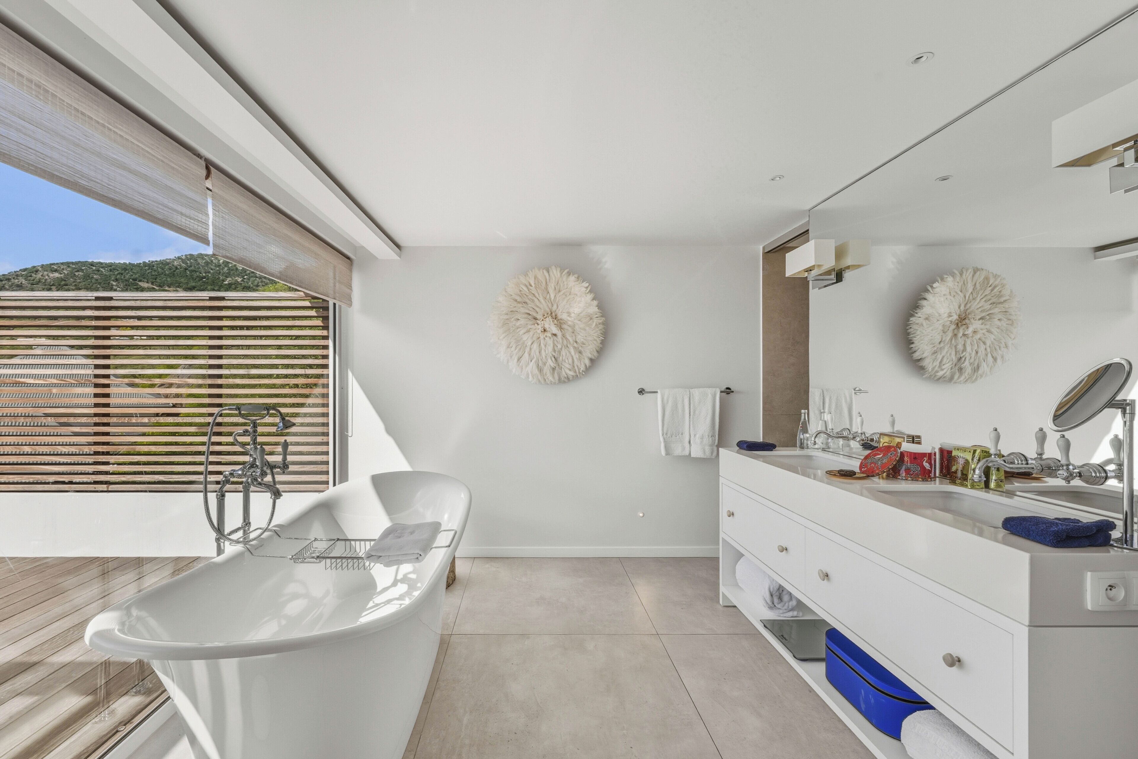 Un baño moderno con una bañera independiente, un espejo grande y un tocador con lavabo.