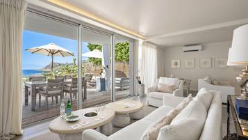 Habitación de hotel moderna con un amplio ventanal corredero que da a un espacio exterior con una mesa, sillas, un sofá y una lámpara.