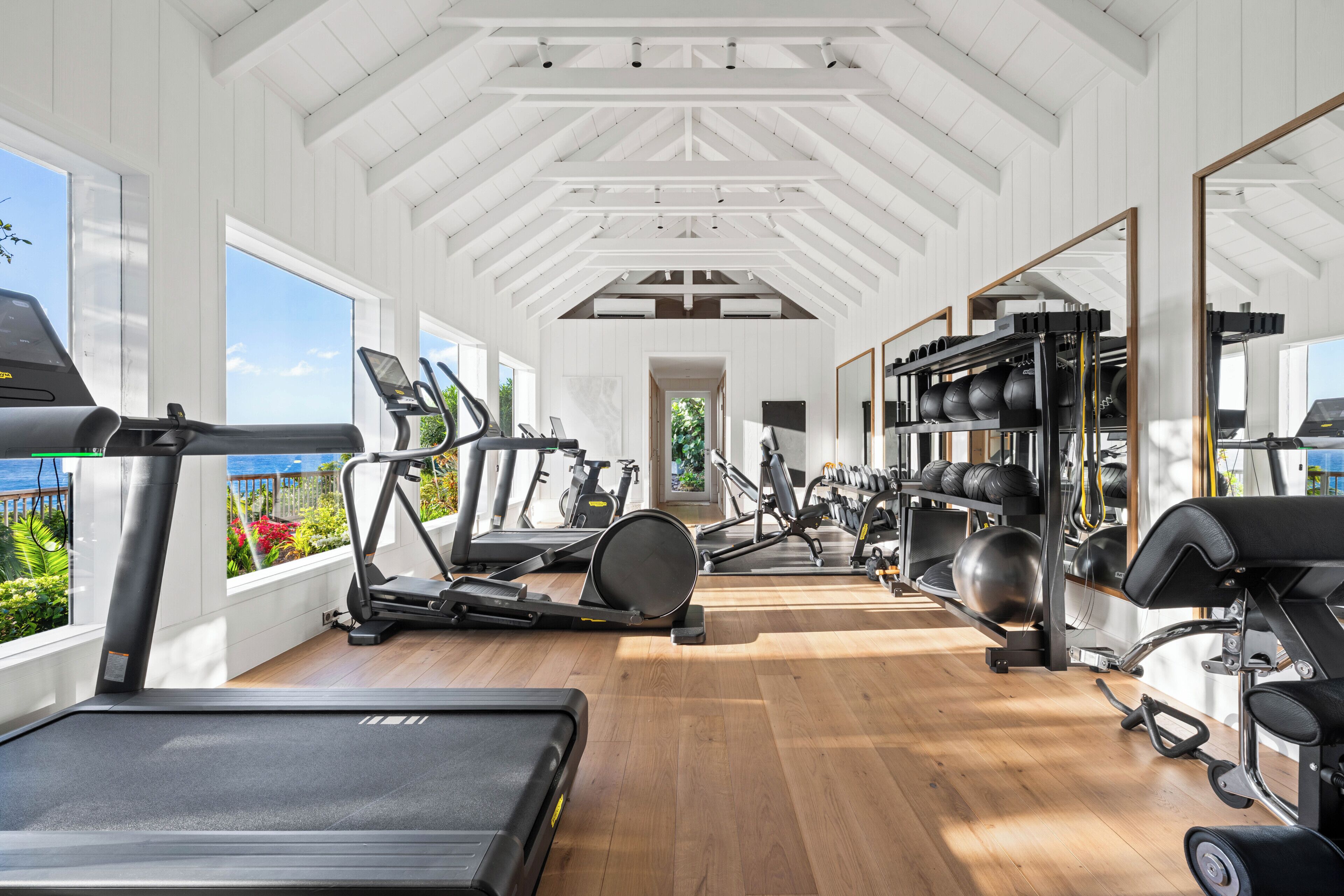 Un gimnasio con cintas de correr, elípticas y equipo de levantamiento de pesas.