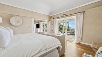 Un dormitorio con cama, escritorio, silla, maleta y vistas al exterior.